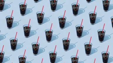 A pattern of a repeated image of a glass of soda with a red straw on a blue background.